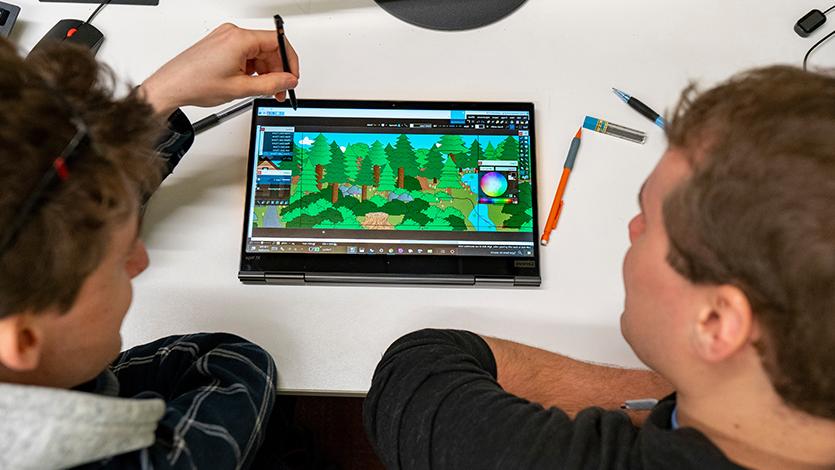 Image of two students working on a tablet that depicts a game design.